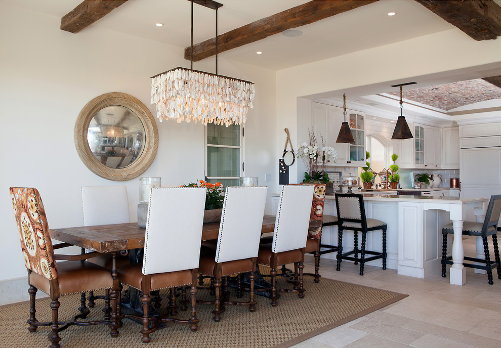 This is an example of a large beach style open plan dining in Orange County with white walls, no fireplace and travertine floors.