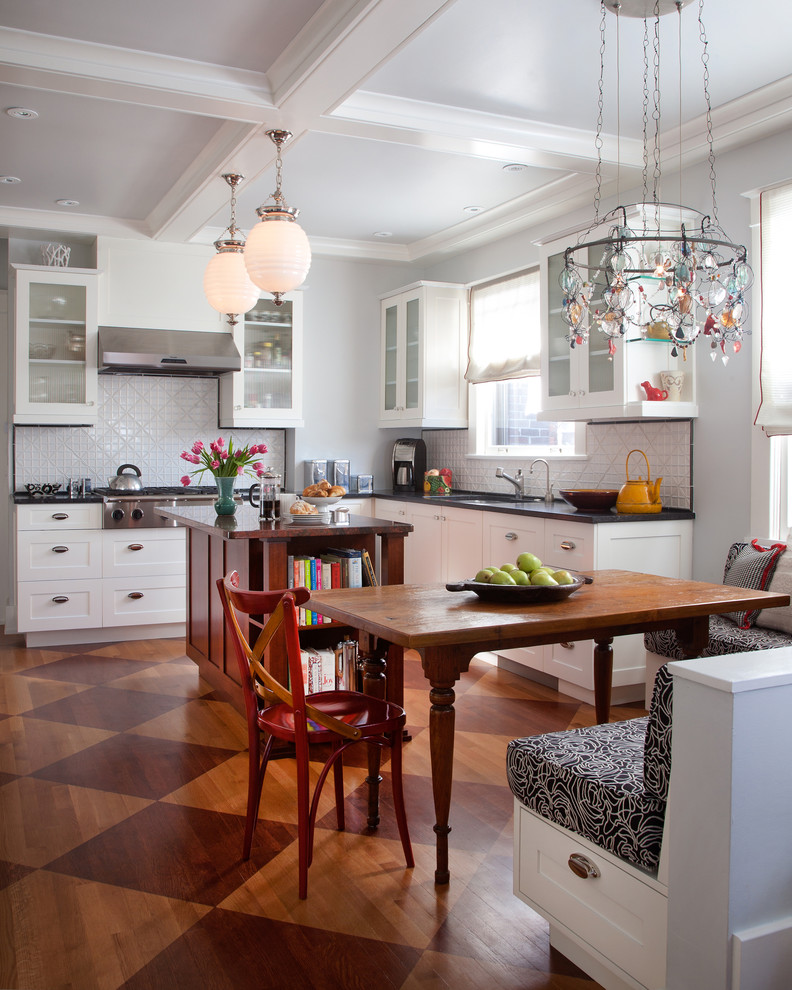 This is an example of a transitional l-shaped eat-in kitchen in Denver with shaker cabinets, white cabinets, white splashback and medium hardwood floors.