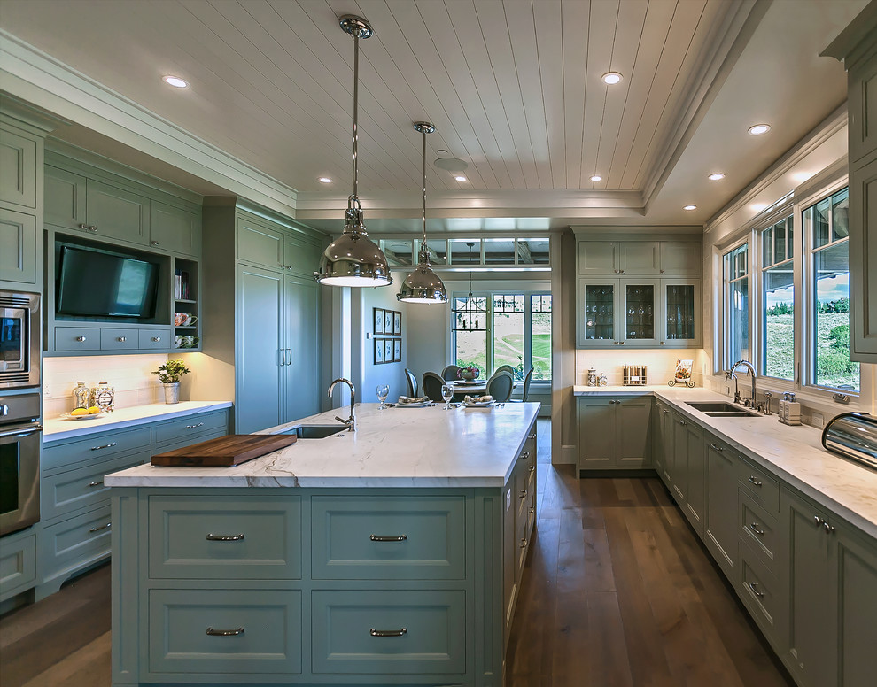 Photo of a mid-sized transitional u-shaped eat-in kitchen in Salt Lake City with a double-bowl sink, shaker cabinets, green cabinets, marble benchtops, white splashback, timber splashback, stainless steel appliances, medium hardwood floors, with island, white benchtop and timber.
