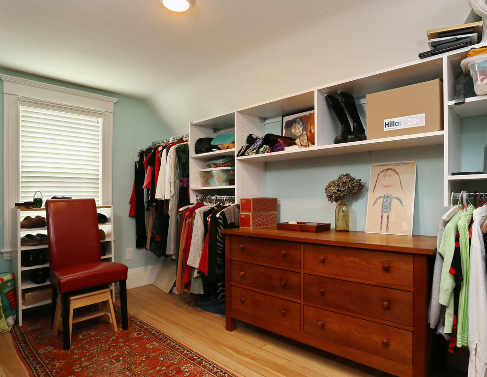Large transitional gender-neutral walk-in wardrobe in Boston with open cabinets, white cabinets and light hardwood floors.
