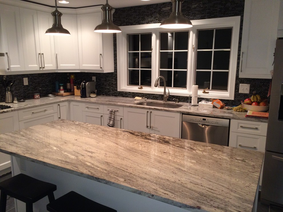 Photo of a large contemporary l-shaped eat-in kitchen in Philadelphia with an undermount sink, shaker cabinets, white cabinets, granite benchtops, black splashback, mosaic tile splashback, stainless steel appliances, porcelain floors and with island.