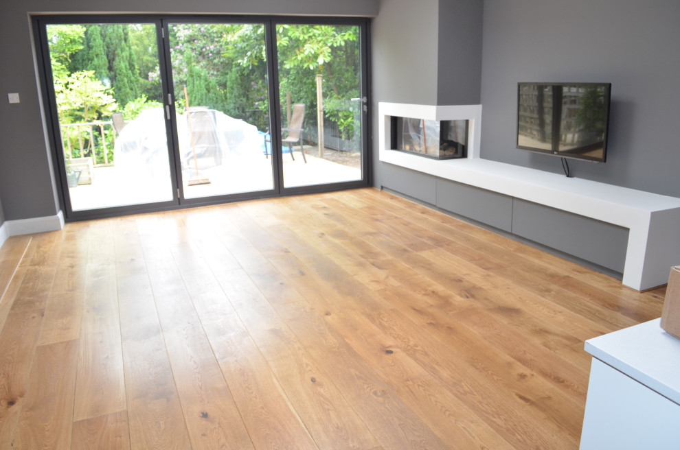 Imagen de salón actual con suelo de madera en tonos medios y suelo marrón
