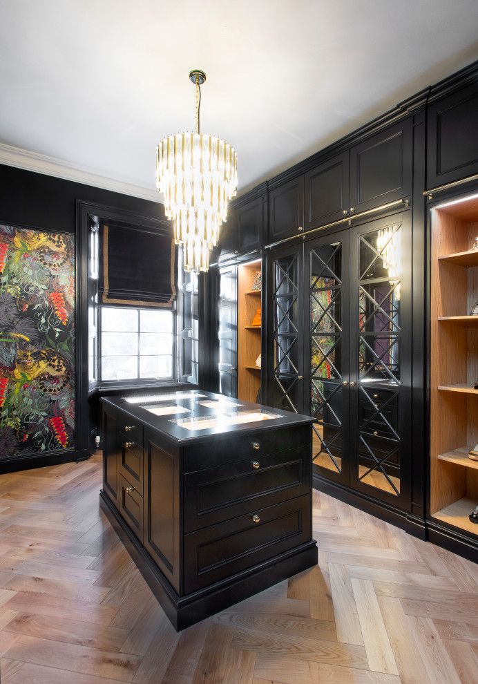 Inspiration for a large classic gender neutral dressing room in Edinburgh with glass-front cabinets, black cabinets, light hardwood flooring and beige floors.