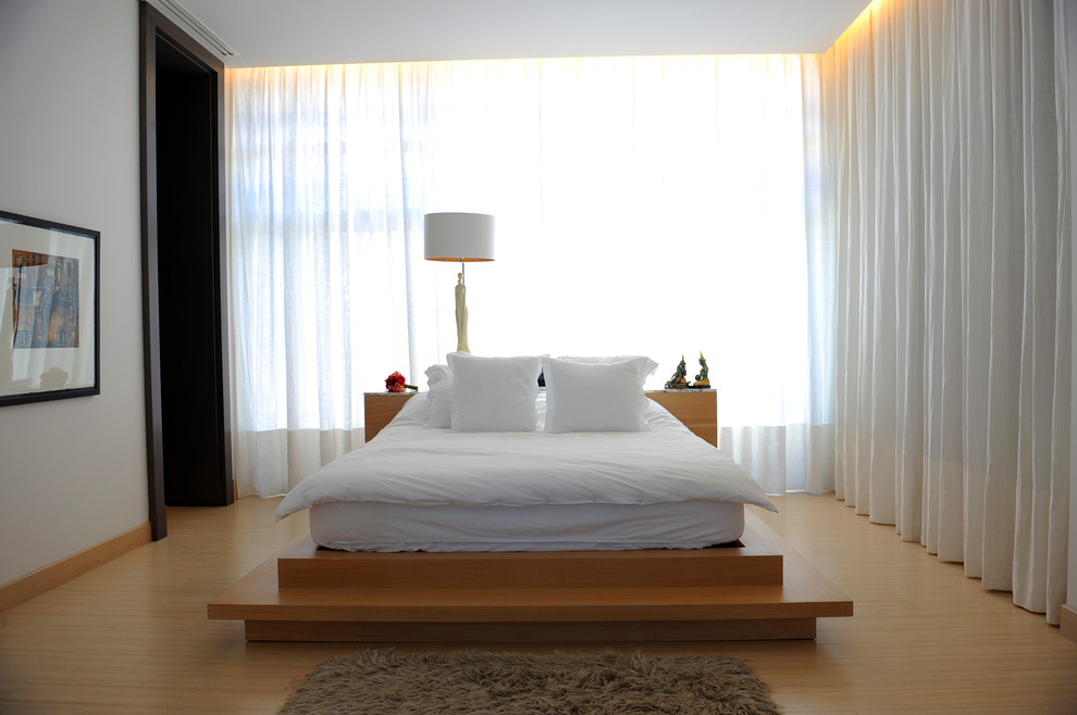 This is an example of a contemporary bedroom in Other with white walls and light hardwood floors.