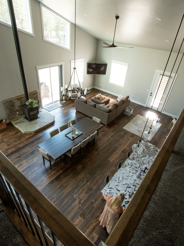 Immagine di un soggiorno american style stile loft con parquet scuro, stufa a legna, cornice del camino in pietra ricostruita e porta TV ad angolo