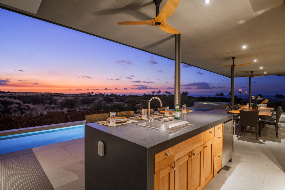 This is an example of a mid-sized tropical single-wall separate kitchen in Hawaii with an undermount sink, flat-panel cabinets, medium wood cabinets, granite benchtops, green splashback, glass tile splashback, stainless steel appliances, porcelain floors, with island and beige floor.