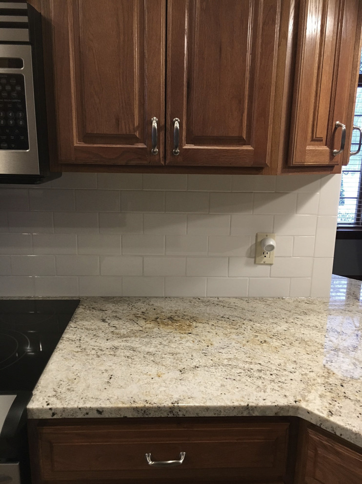 Eat-in kitchen - large transitional u-shaped medium tone wood floor eat-in kitchen idea with an undermount sink, raised-panel cabinets, medium tone wood cabinets, granite countertops, white backsplash, ceramic backsplash, stainless steel appliances and an island