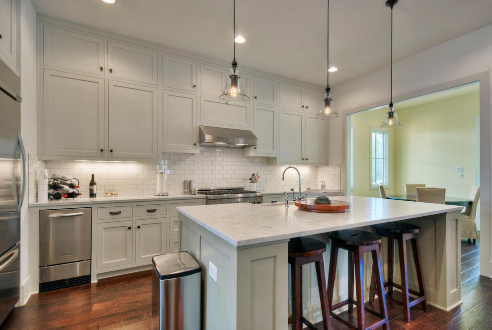 This is an example of a traditional kitchen in Austin with subway tile splashback, stainless steel appliances, shaker cabinets, grey cabinets, white splashback and granite benchtops.