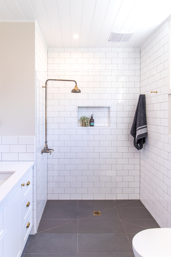 Small transitional master bathroom in Melbourne with shaker cabinets, white cabinets, an open shower, a two-piece toilet, white tile, subway tile, beige walls, porcelain floors, an undermount sink and engineered quartz benchtops.