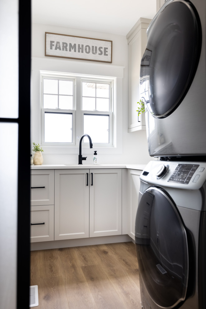 Klassisk inredning av ett mellanstort vit vitt kök, med en undermonterad diskho, skåp i shakerstil, vita skåp, bänkskiva i kvarts, rostfria vitvaror, mellanmörkt trägolv, en köksö och flerfärgat golv