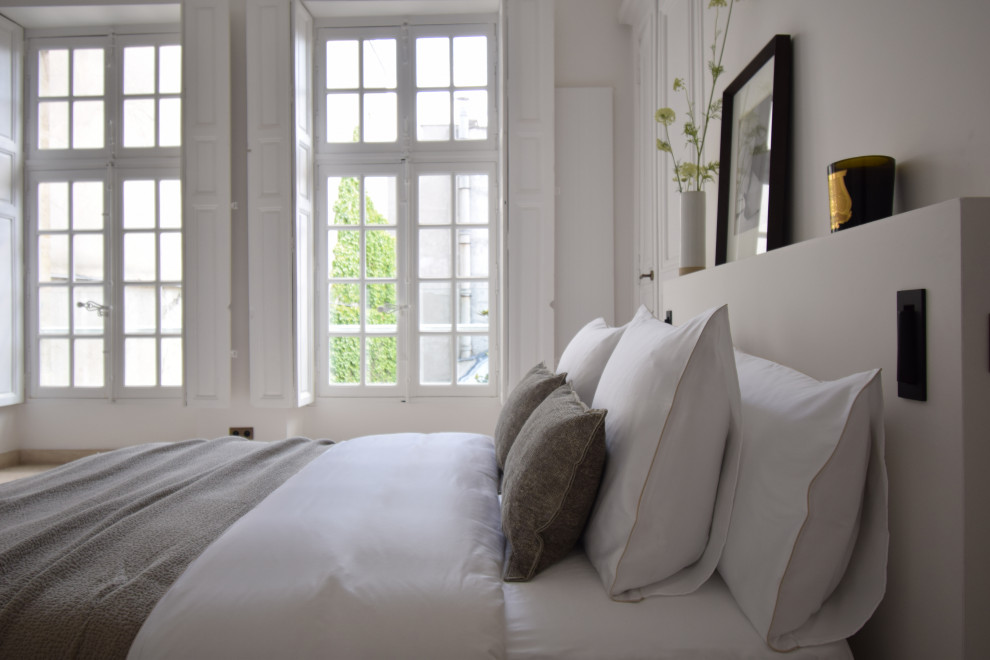 Photo of a transitional bedroom in Paris with white walls.