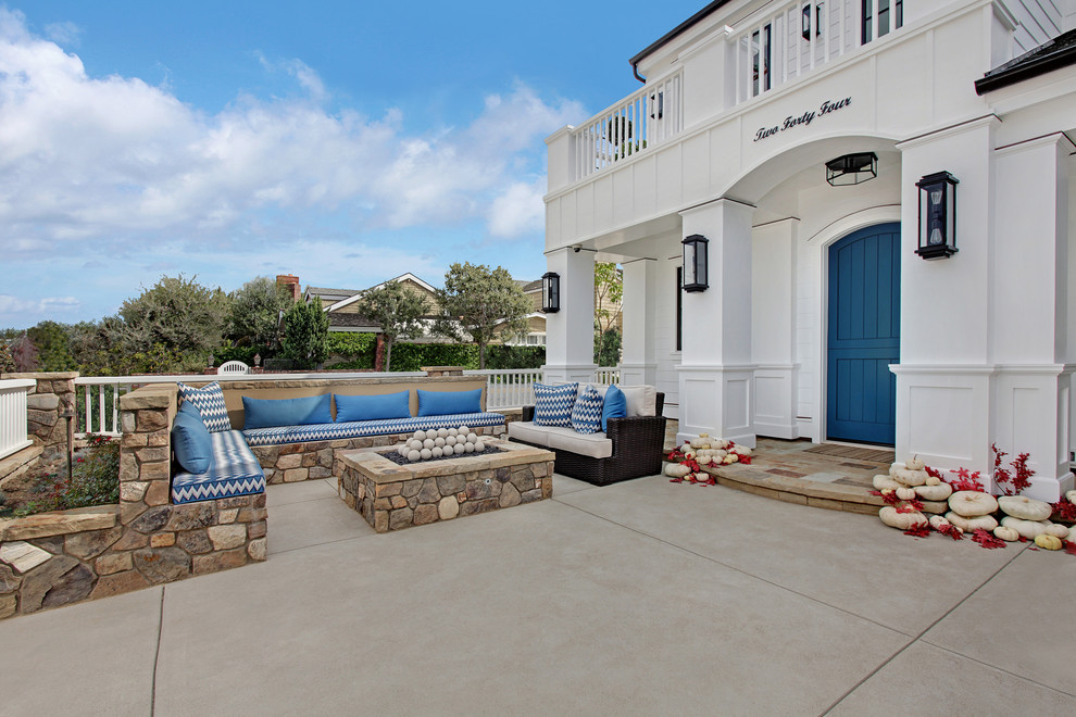 This is an example of a beach style front yard patio in Orange County with a fire feature, concrete slab and no cover.