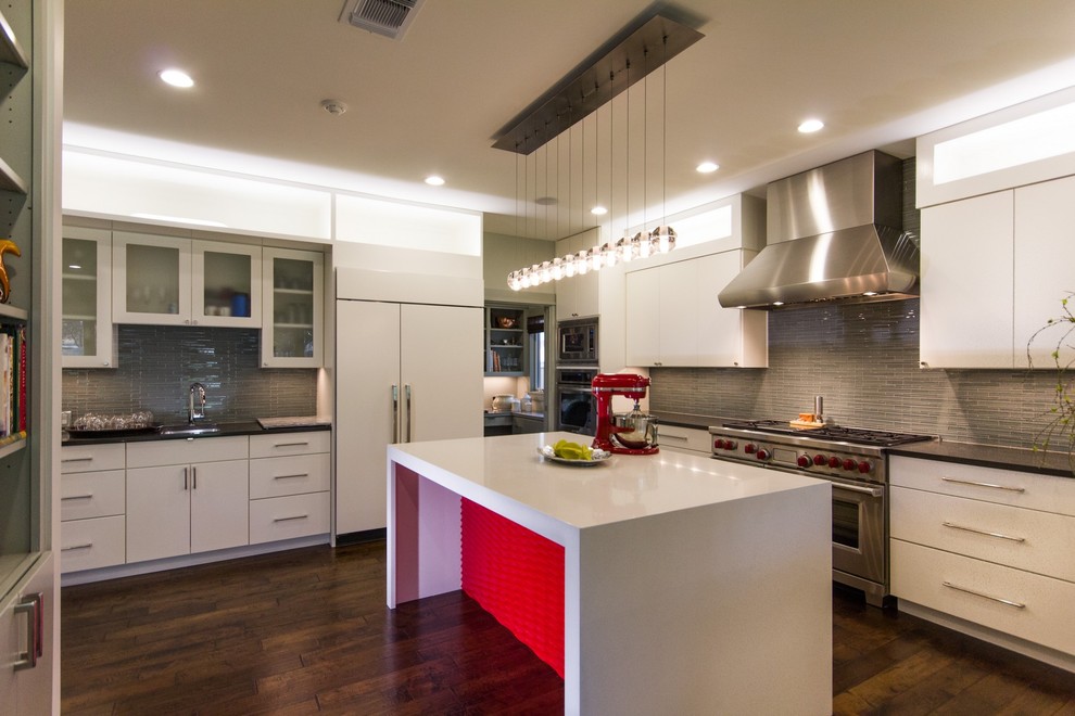 Large traditional u-shaped eat-in kitchen in Austin with an undermount sink, flat-panel cabinets, white cabinets, quartz benchtops, green splashback, glass tile splashback, stainless steel appliances, dark hardwood floors, with island and brown floor.