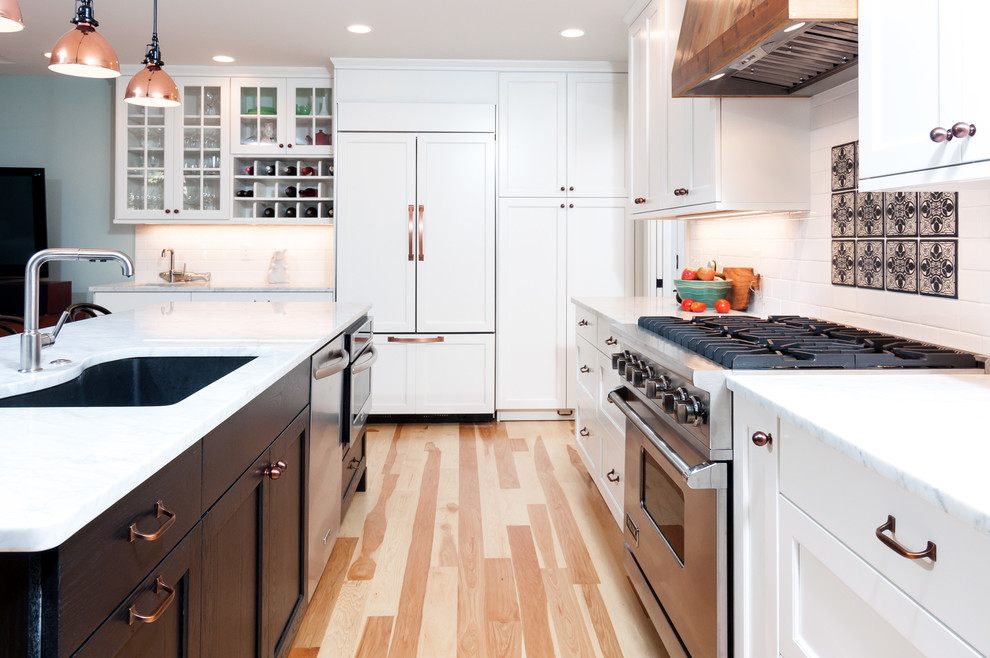 Example of a mid-sized transitional l-shaped light wood floor and brown floor open concept kitchen design in Detroit with an undermount sink, recessed-panel cabinets, white cabinets, quartzite countertops, white backsplash, subway tile backsplash, stainless steel appliances and an island