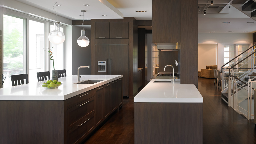 Large modern l-shaped eat-in kitchen in Chicago with an integrated sink, flat-panel cabinets, dark wood cabinets, marble benchtops, panelled appliances, dark hardwood floors and with island.