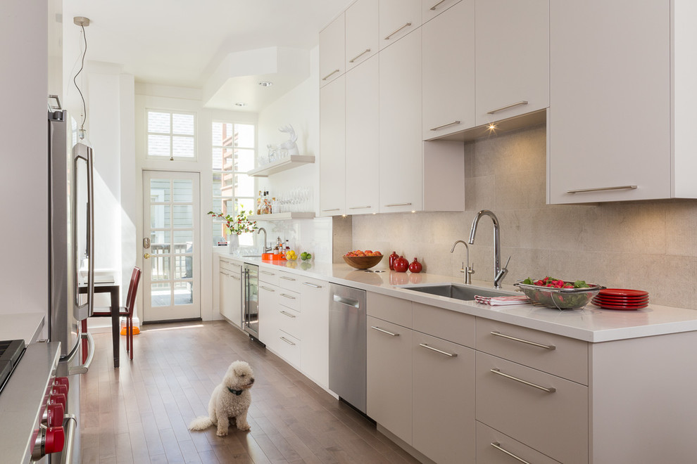 Modern inredning av ett mellanstort kök, med en enkel diskho, släta luckor, vita skåp, bänkskiva i kvarts, beige stänkskydd, stänkskydd i stenkakel, rostfria vitvaror och mellanmörkt trägolv