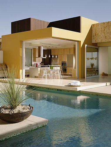 Photo of a large contemporary backyard l-shaped infinity pool in Los Angeles with a pool house and concrete slab.