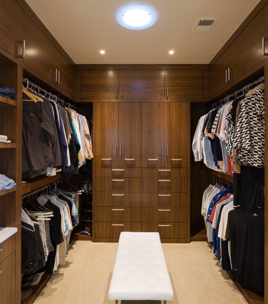 Photo of a contemporary gender-neutral walk-in wardrobe in Albuquerque with dark wood cabinets and beige floor.