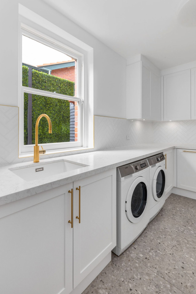 Design ideas for a large modern galley utility room in Melbourne with a submerged sink, shaker cabinets, engineered stone countertops, white worktops, white cabinets, white splashback, metro tiled splashback, porcelain flooring and a side by side washer and dryer.