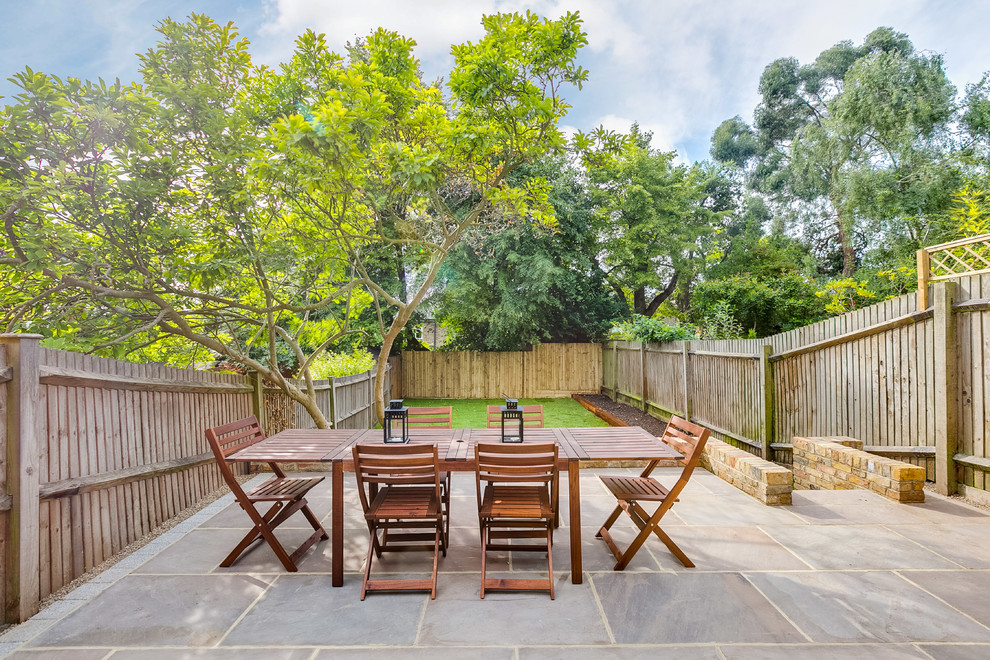 This is an example of a mid-sized transitional backyard patio in London with no cover.