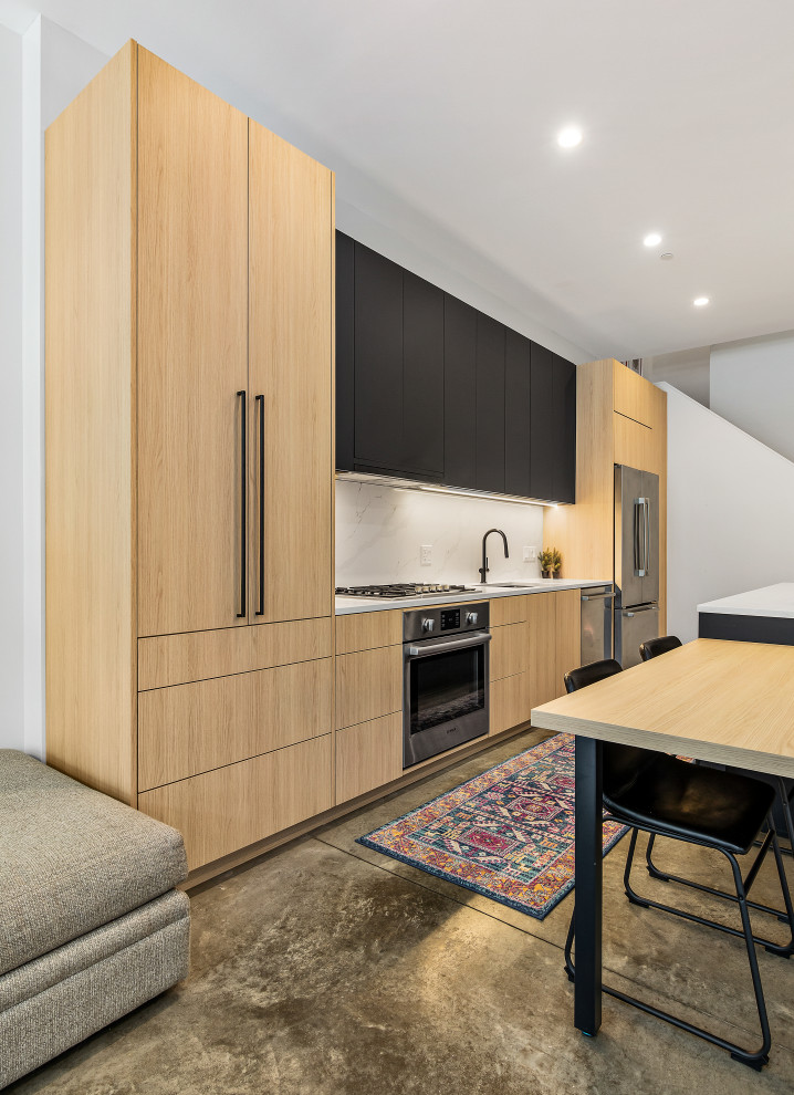 Свежая идея для дизайна: кухня-гостиная среднего размера в стиле модернизм с врезной мойкой, плоскими фасадами, техникой из нержавеющей стали, бетонным полом и островом - отличное фото интерьера