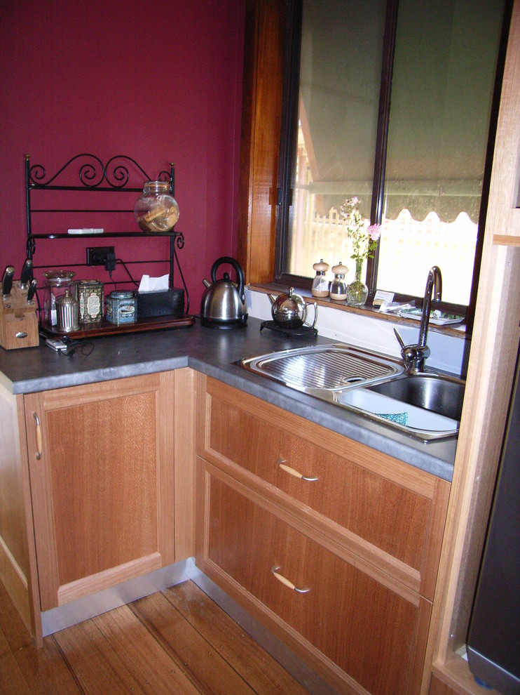 This is an example of a mid-sized contemporary galley eat-in kitchen in Melbourne with a drop-in sink, shaker cabinets, light wood cabinets, quartz benchtops, red splashback, glass sheet splashback, coloured appliances, light hardwood floors and with island.