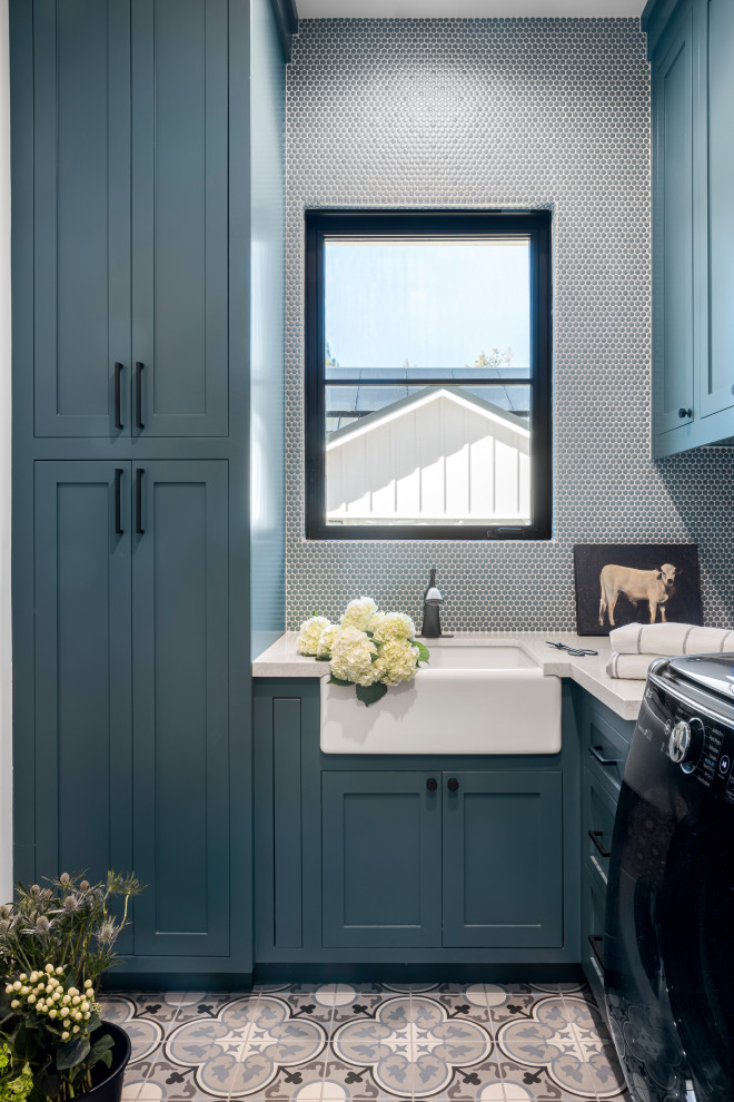 Photo of an expansive country u-shaped dedicated laundry room in San Francisco with a farmhouse sink, shaker cabinets, turquoise cabinets, quartz benchtops, blue splashback, mosaic tile splashback, blue walls, ceramic floors, a side-by-side washer and dryer, multi-coloured floor and white benchtop.