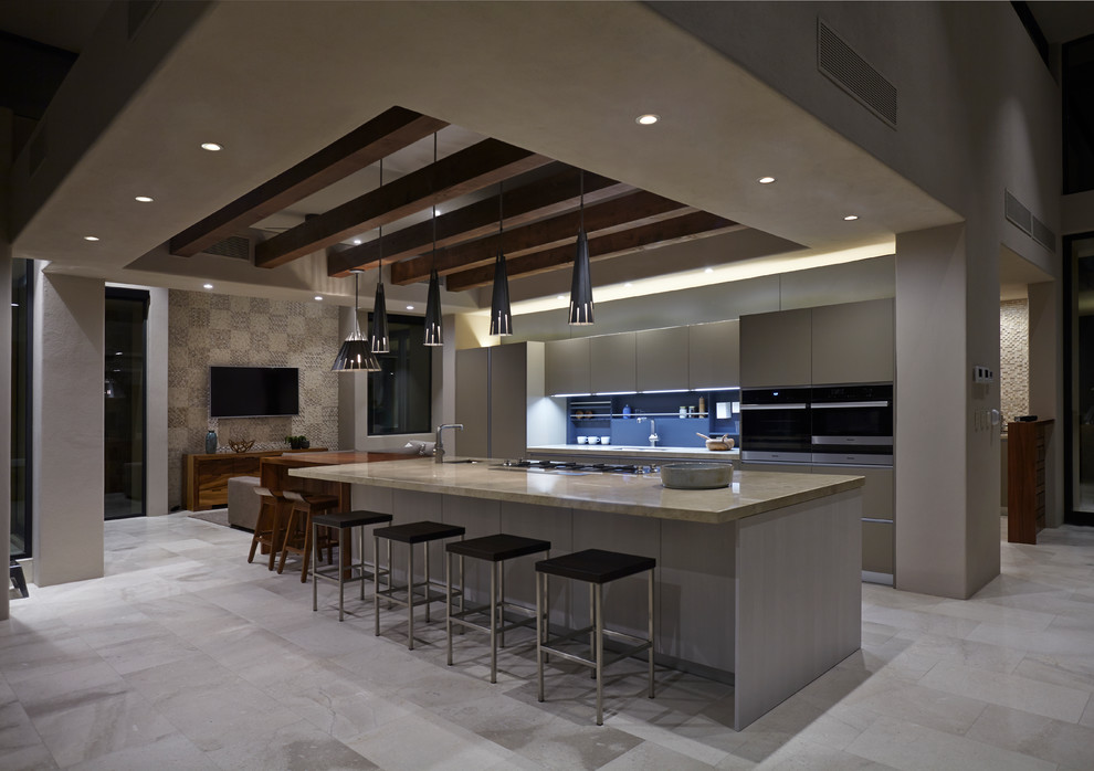 Large galley eat-in kitchen in Other with an undermount sink, flat-panel cabinets, beige cabinets, limestone benchtops, grey splashback, stainless steel appliances, limestone floors, with island and grey floor.