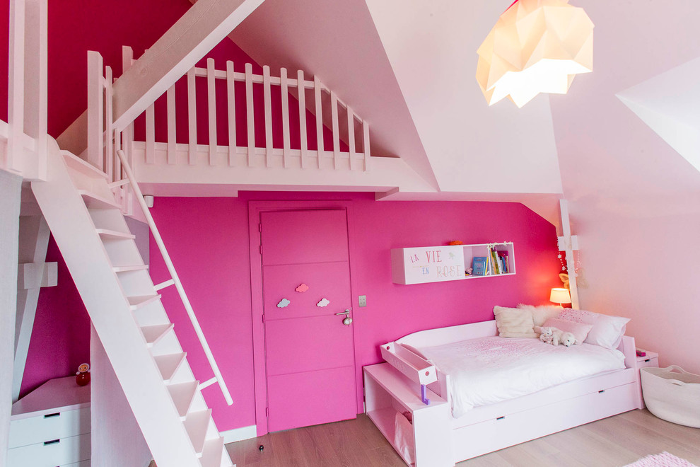 Photo of a large contemporary kids' bedroom for kids 4-10 years old and girls in Paris with pink walls, brown floor and light hardwood floors.