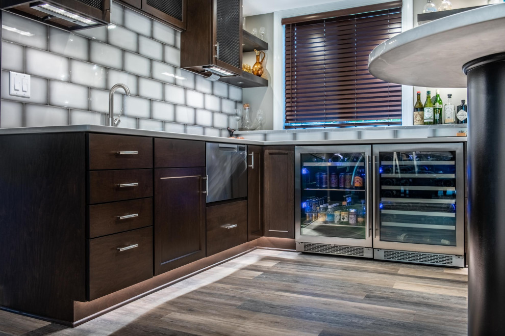 This is an example of a mid-sized contemporary u-shaped wet bar in Other with an undermount sink, flat-panel cabinets, brown cabinets, quartzite benchtops, grey splashback, ceramic splashback, vinyl floors, brown floor and grey benchtop.