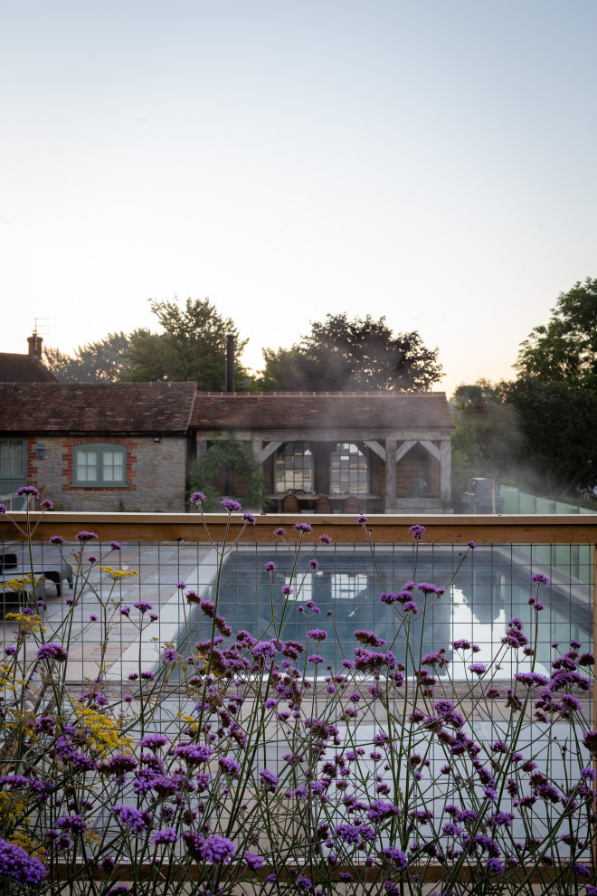 Geometrischer, Großer Landhaus Garten im Sommer, hinter dem Haus mit Blumenbeet und Natursteinplatten in Oxfordshire
