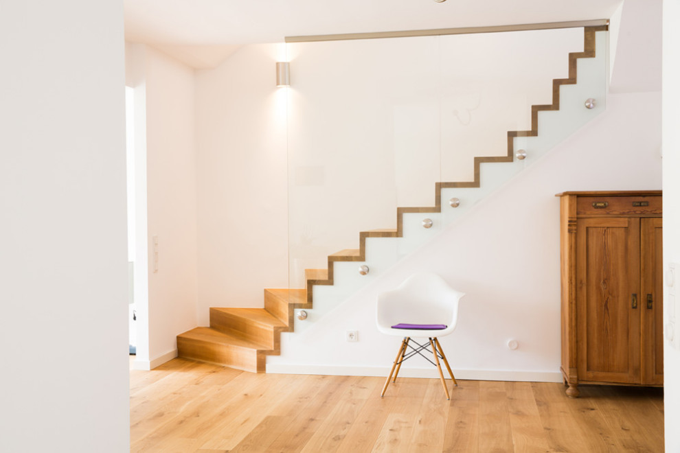 Cette image montre un grand escalier courbe design avec des marches en bois, des contremarches en bois et un garde-corps en verre.