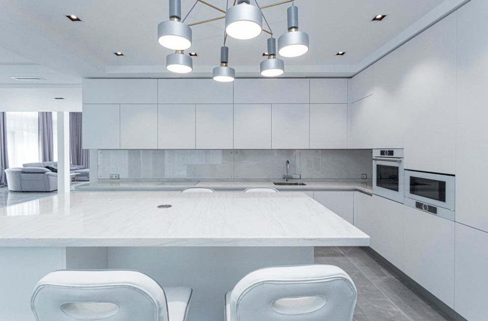 Large contemporary l-shaped kitchen in Saint Petersburg with a single-bowl sink, flat-panel cabinets, white cabinets, solid surface benchtops, white splashback, white appliances, porcelain floors, with island, grey floor, white benchtop and exposed beam.