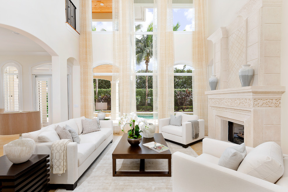 This is an example of a transitional open concept living room in Miami with beige walls, a two-sided fireplace, a stone fireplace surround and brown floor.