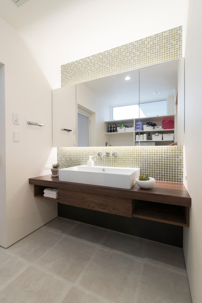 Design ideas for a mid-sized modern powder room in Other with open cabinets, brown cabinets, beige tile, glass tile, white walls, a drop-in sink, solid surface benchtops, grey floor and brown benchtops.
