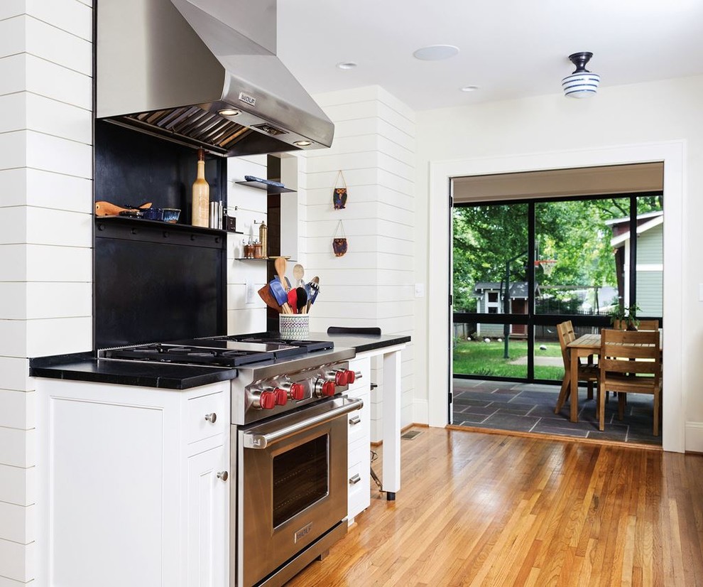 Mid-sized transitional l-shaped light wood floor kitchen pantry photo in Denver with recessed-panel cabinets, black cabinets, laminate countertops, black backsplash, cement tile backsplash, stainless steel appliances and no island