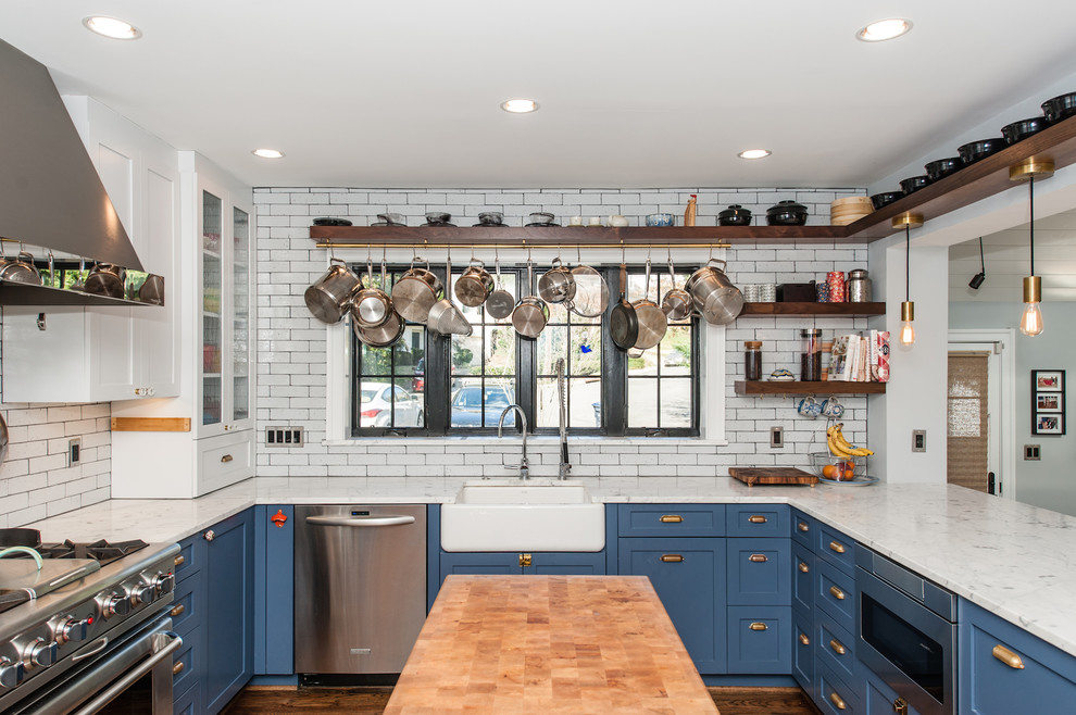 Design ideas for a mid-sized traditional u-shaped open plan kitchen in DC Metro with a farmhouse sink, recessed-panel cabinets, blue cabinets, marble benchtops, white splashback, subway tile splashback, stainless steel appliances, dark hardwood floors, with island and brown floor.
