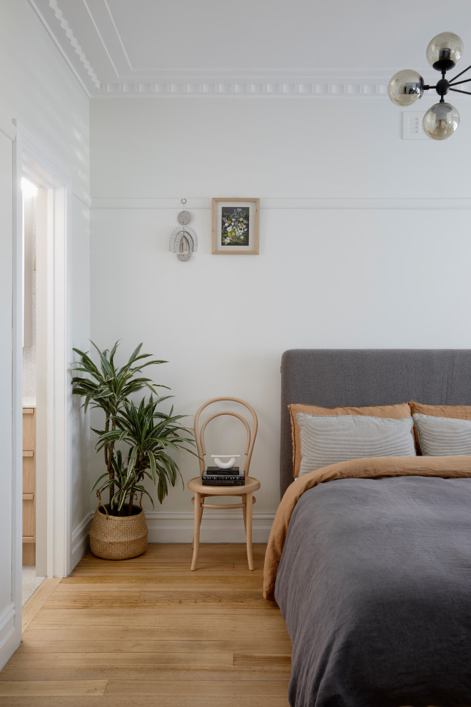 This is an example of a modern bedroom in Melbourne with white walls, medium hardwood floors and brown floor.