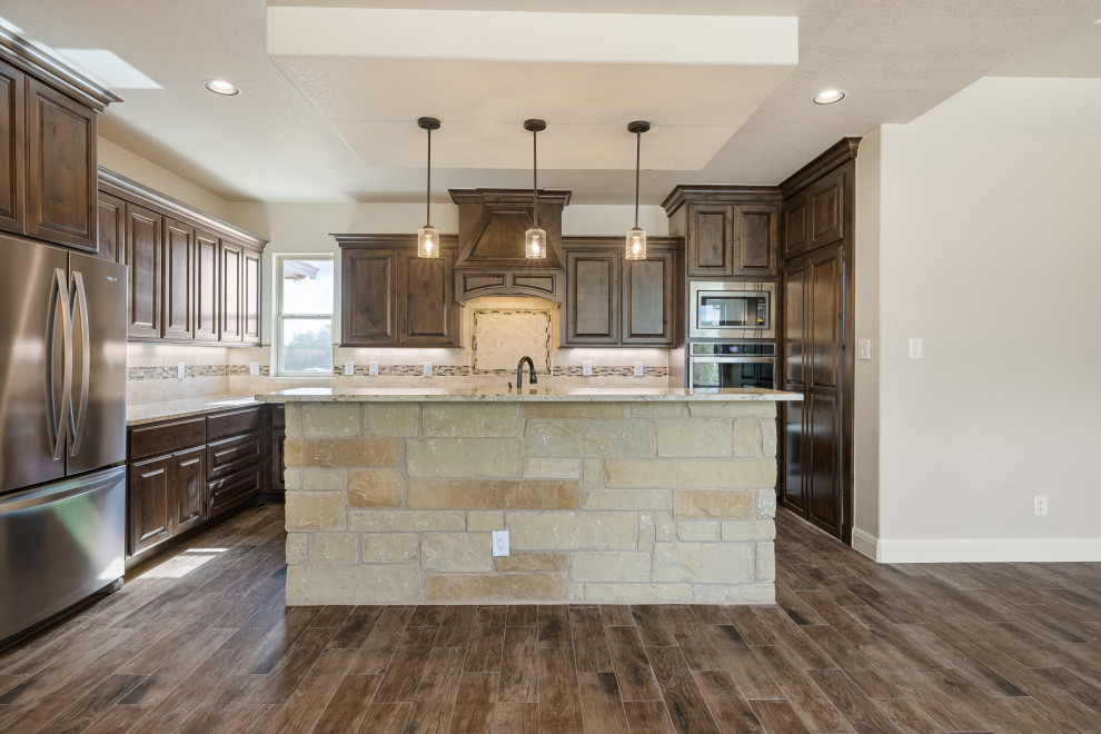 Mountain style medium tone wood floor kitchen photo in Austin with shaker cabinets, dark wood cabinets, granite countertops, stainless steel appliances and an island