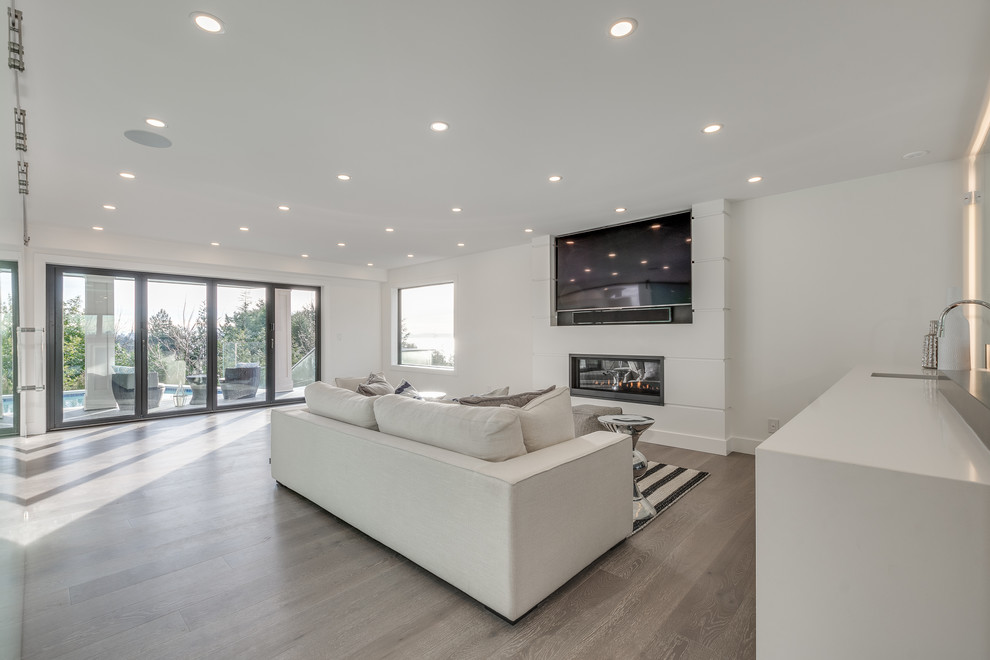 Mid-sized modern open concept family room in Vancouver with white walls, light hardwood floors, a ribbon fireplace, a plaster fireplace surround, a built-in media wall and grey floor.