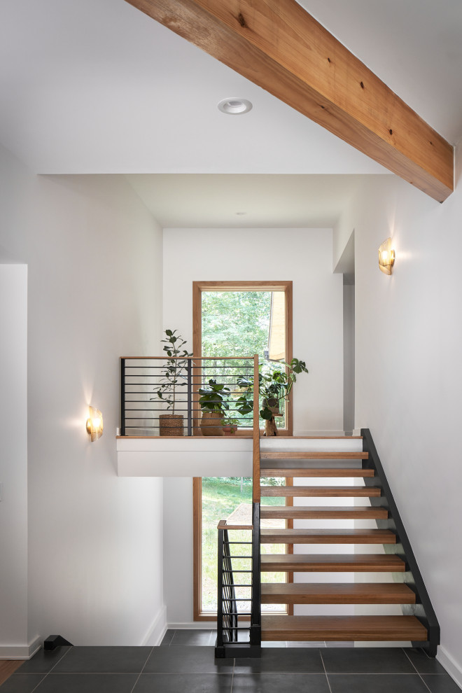 Inspiration for a mid-sized midcentury foyer in Atlanta with white walls, porcelain floors, a single front door, a black front door, black floor and exposed beam.