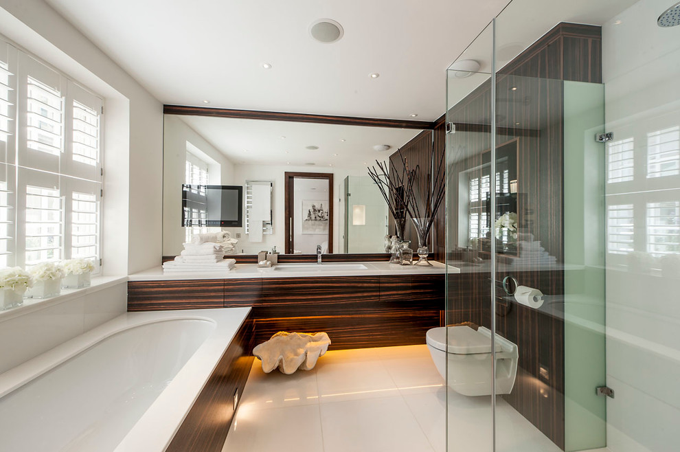 Contemporary bathroom in London with flat-panel cabinets, an alcove shower, a wall-mount toilet, beige tile and an undermount tub.