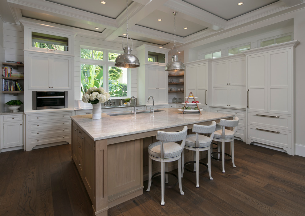 This is an example of a beach style u-shaped kitchen in Miami with an undermount sink, shaker cabinets, white cabinets, white splashback, panelled appliances, dark hardwood floors and with island.