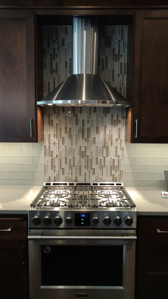 Eat-in kitchen - large transitional eat-in kitchen idea in Seattle with shaker cabinets, dark wood cabinets, quartz countertops, beige backsplash, glass tile backsplash and stainless steel appliances