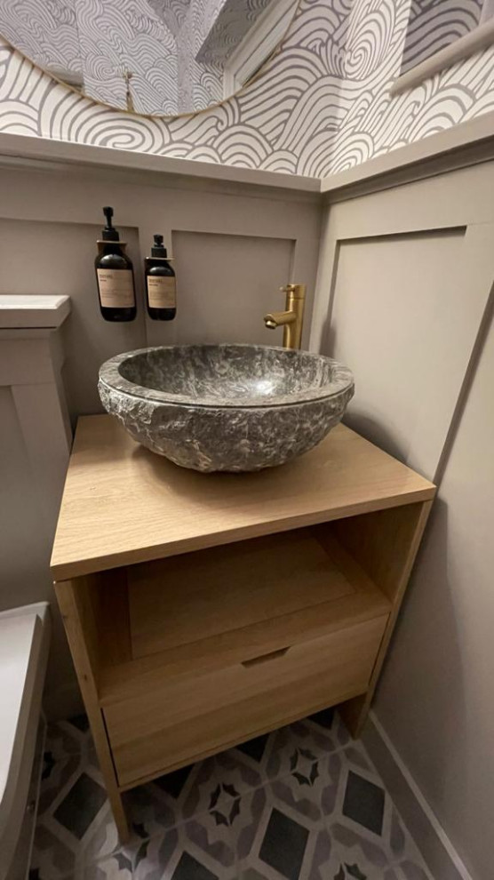 This is an example of a small traditional powder room in Surrey with open cabinets, light wood cabinets, a one-piece toilet, ceramic floors, wood benchtops, grey floor, a freestanding vanity, vaulted and panelled walls.