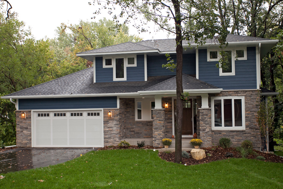 This is an example of a large transitional two-storey blue exterior in Minneapolis with stone veneer and a hip roof.