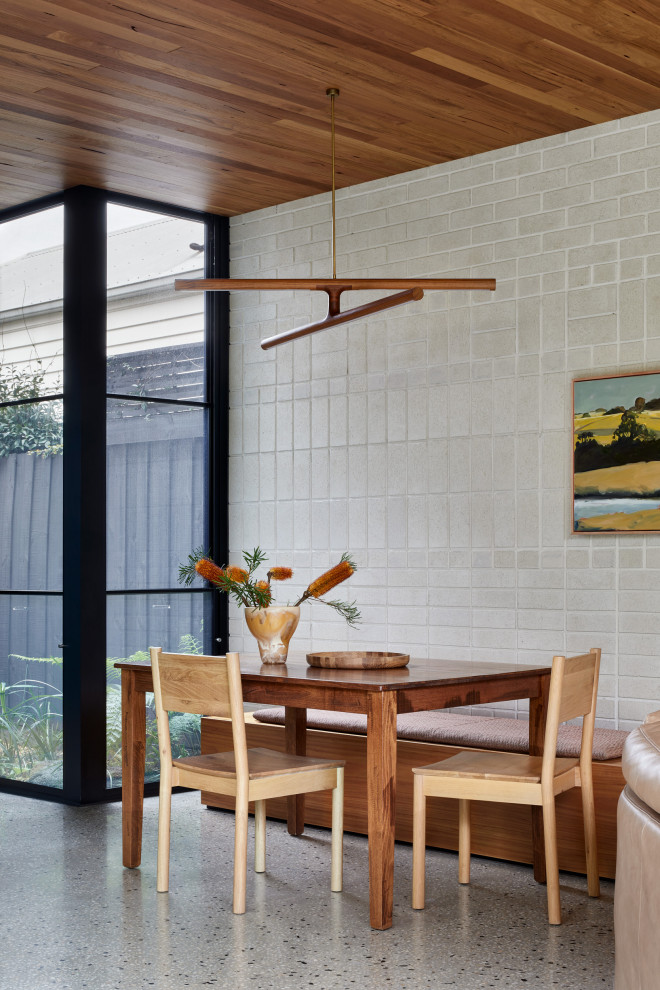 Ispirazione per una piccola sala da pranzo aperta verso il soggiorno minimalista con pareti grigie, pavimento in cemento, pavimento grigio, soffitto in legno e pareti in mattoni