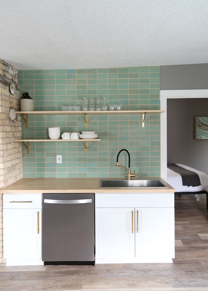 Open concept kitchen - small transitional l-shaped light wood floor and brown floor open concept kitchen idea in Minneapolis with a drop-in sink, flat-panel cabinets, white cabinets, wood countertops, green backsplash, ceramic backsplash, stainless steel appliances, no island and brown countertops