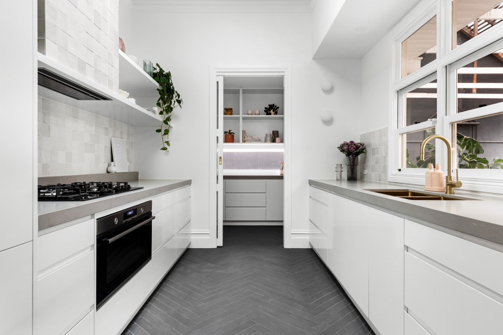 Modern inredning av ett mellanstort vit vitt kök, med en dubbel diskho, vita skåp, bänkskiva i betong, grått stänkskydd, stänkskydd i keramik, rostfria vitvaror, klinkergolv i keramik och svart golv