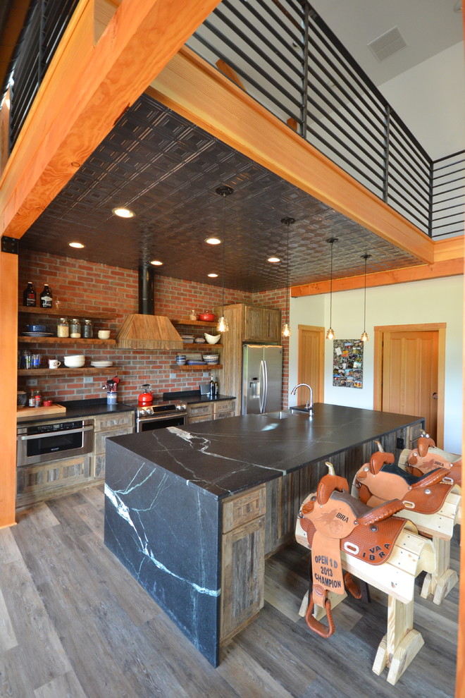 Example of a mid-sized mountain style single-wall vinyl floor and brown floor kitchen design with open cabinets, medium tone wood cabinets, soapstone countertops, an island, an integrated sink, red backsplash, stainless steel appliances and brick backsplash